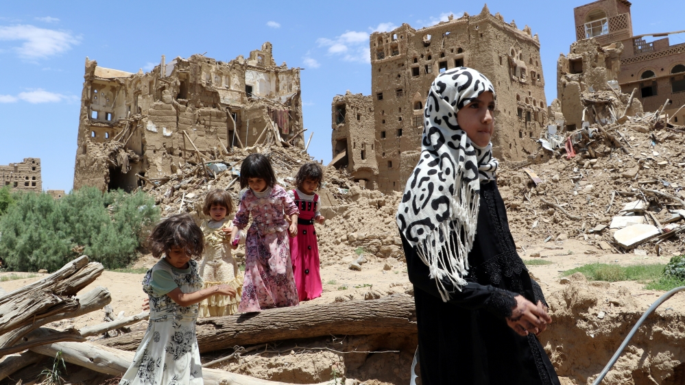 Girls stand past houses destroyed by Saudi-led air strikes in an outskirt of the northwestern city of Saada
