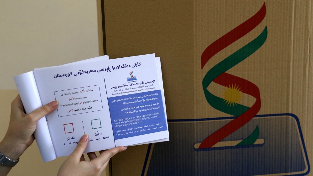 An employee from the Independent High Electoral Referendum Commission holds a voting ballot book at a voting station before tomorrow's planned referendum for the Kurdistan region [AFP]