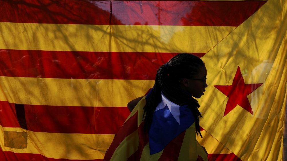 A woman wearing an Estelada (Catalan separatist flag) walks past another big Estelada during a gathering in support of the banned October 1st independence referendum in Barcelona