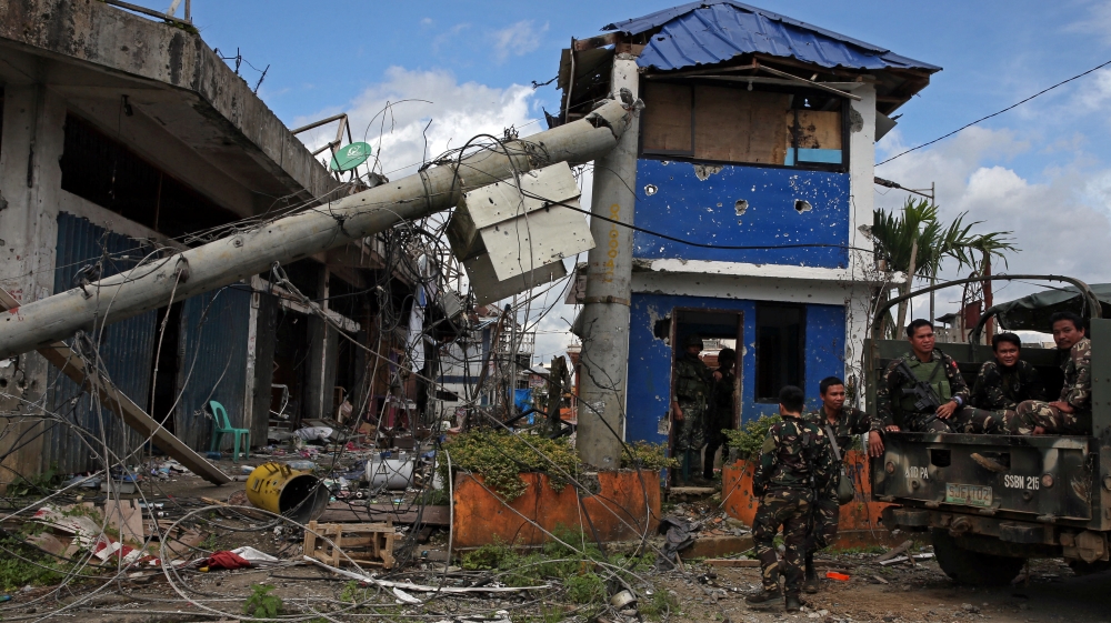 Soldiers stand on guard in front of damaged buildings after government troops cleared the area from pro-Islamic State militant groups inside a war-torn area in Bangolo town, Marawi City