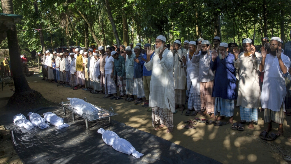 Bangladeshi villagers pray by the bodies of Rohingya Muslim children who drowned while crossing over from Myanmar into Bangladesh after their boat capsized near Shah Porir Dwip, Bangladesh, Monday, Oc