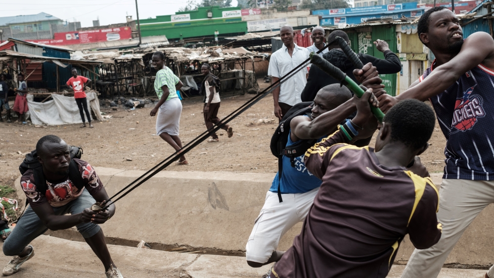 Demonstrators simulate throwing a stone towards a police station on October 16, 2017, in Kisumu, to demand the removal of officials from national election oversight body [Yasuyoshi Chiba/AFP/Getty Images]