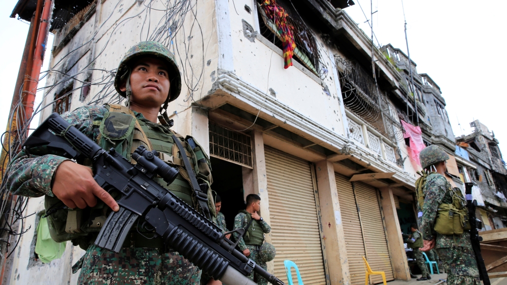 Government soldiers stand guard in front of damaged building and houses in Sultan Omar Dianalan boulevard at Mapandi district in Marawi city