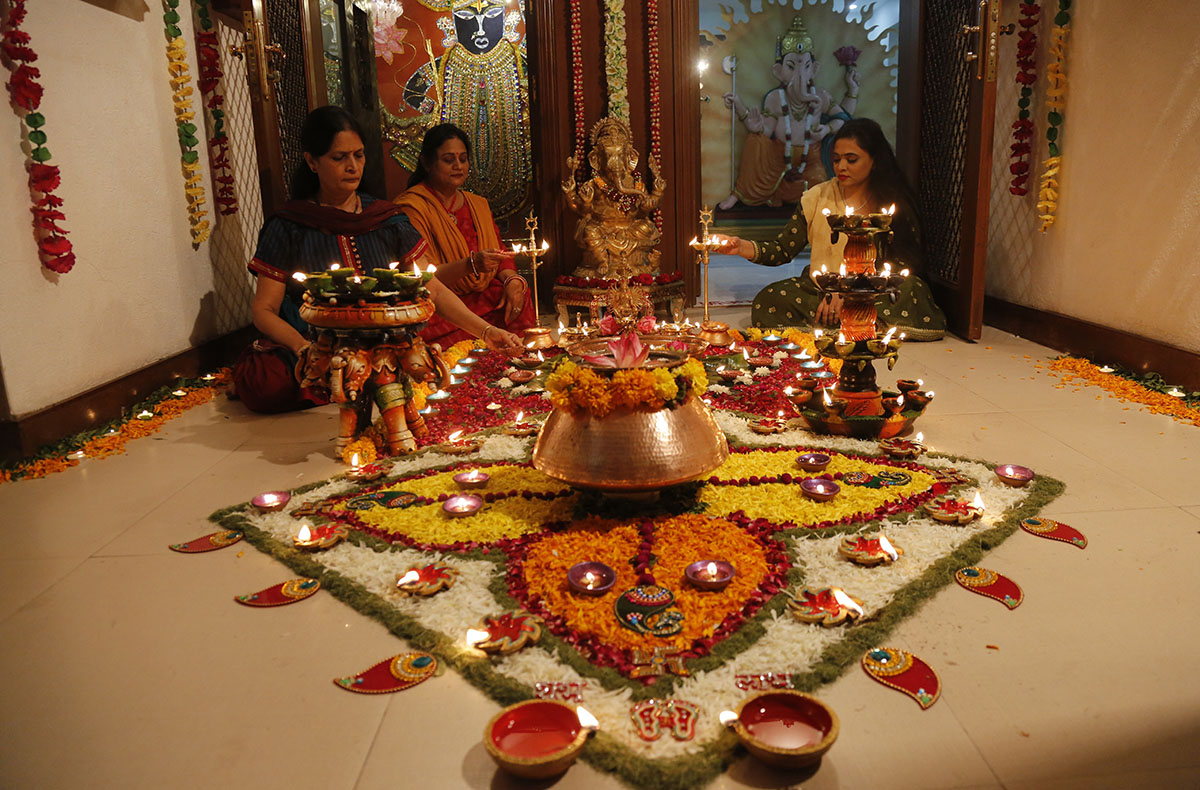 Members of an Indian Hindu family light earthen lamps on a rangoli, a hand decorated pattern on the floor, as part of Diwali festivities in Ahmadabad, India, Thursday, Oct. 19, 2017. Diwali, the festi