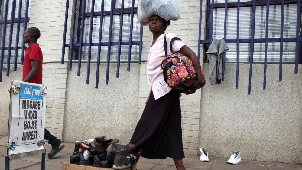 A woman walks past newspaper advertising poster on the street in central Harare [Philimon Bulawayo/Reuters]