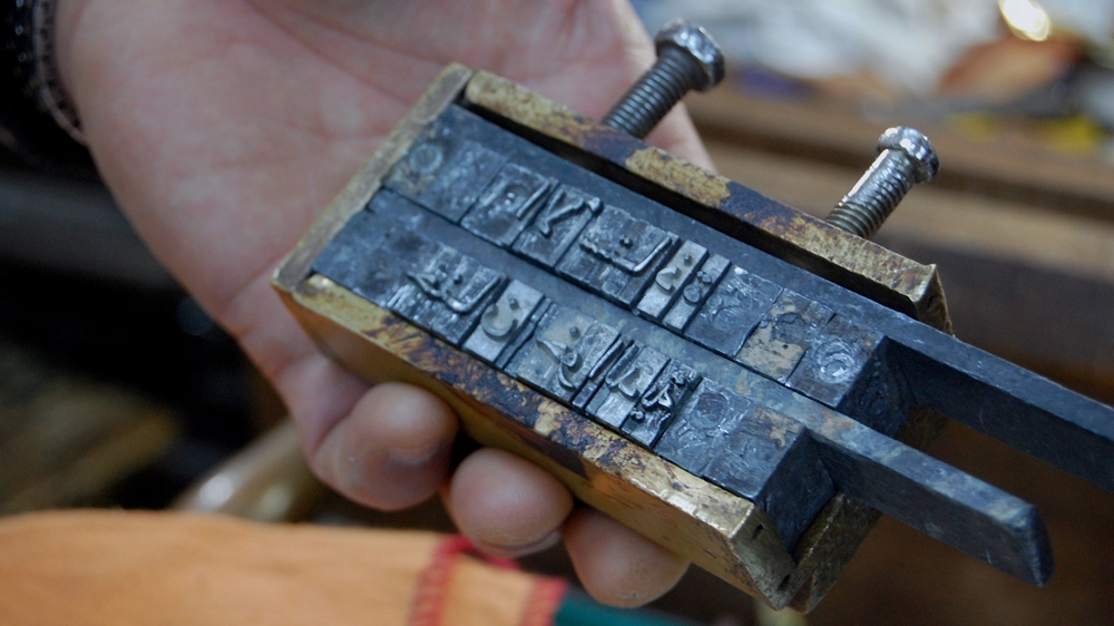 Ben Sassi uses stamps to adorn the books with gold lettering [Jillian Kestler-D'Amours/Al Jazeera]