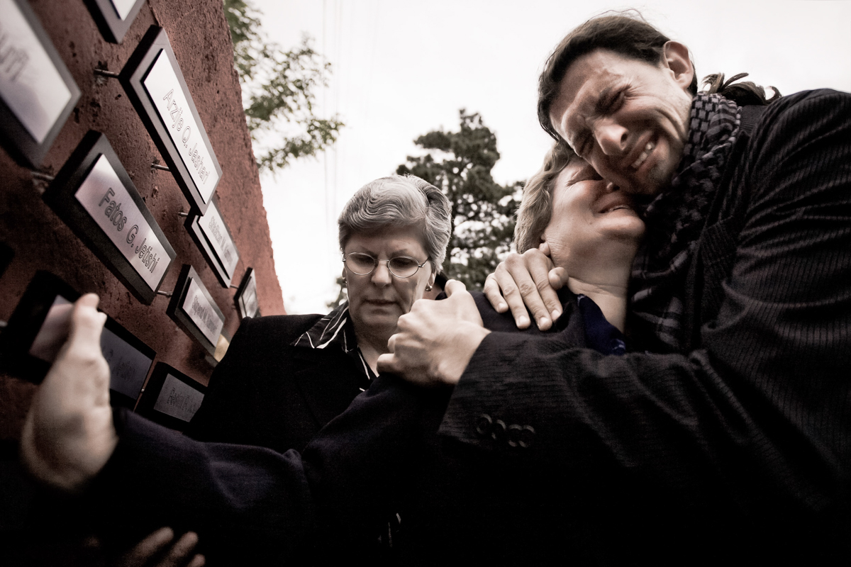 Members of a Kosovar family cry at the memory of their loved ones killed or missing, their names are written on the plates of the Wall of Memory of Gjacova