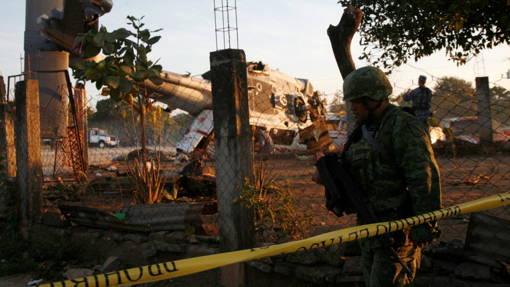 Soldiers stand guard next to a military helicopter - Mexico