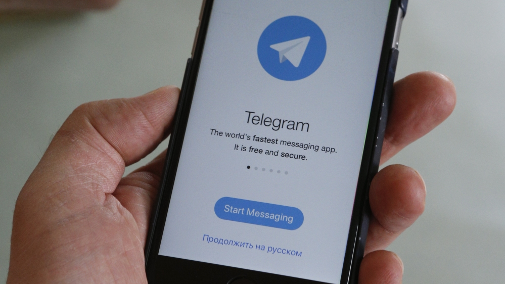 People pose with smartphones, with the Telegram logo seen on a screen, in this picture illustration