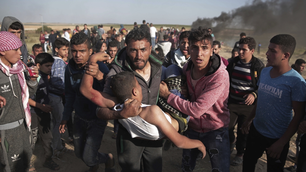 Palestinian protesters carry a wounded man who was shot by Israeli troops during the protests [Khalil Hamra/AP]