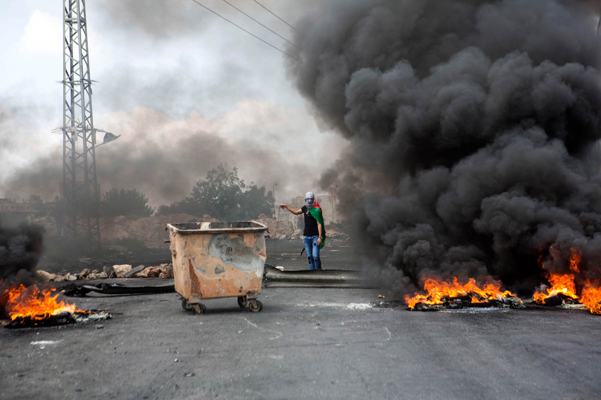Palestinians use burned tire to obstruct the view of the Israeli snippers during clashes near the Bet El Israeli compound and settlement, North of Ramallah.