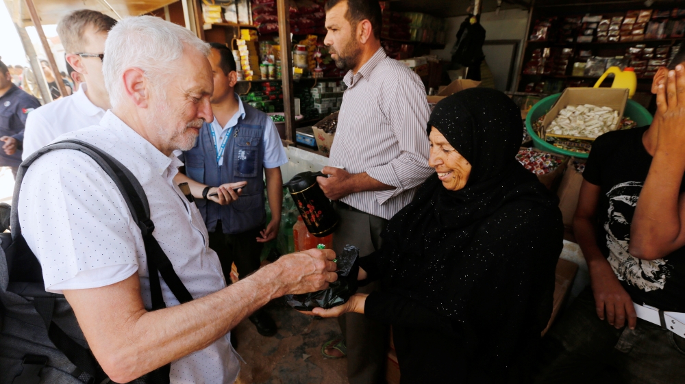 A Syrian refugee woman offers sweets to Britain''s opposition leader Jeremy Corbyn during his visit to Al Zaatari refugee camp, in the Jordanian city of Mafraq
