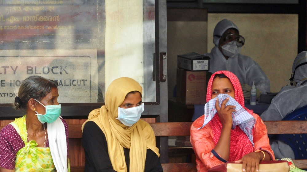 People wear masks as they wait outside a casualty ward at a hospital in Kozhikode