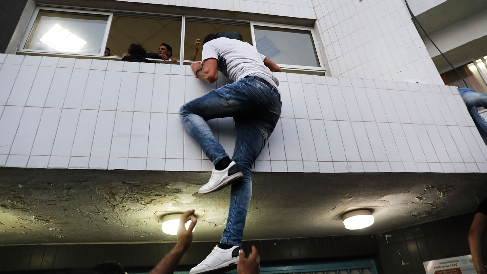 A man tries climb into a hospital window to see a relative who was shot after the hospital closed its doors due to an overflow of patients on May 14 in Gaza City [Spencer Platt/Getty Images]