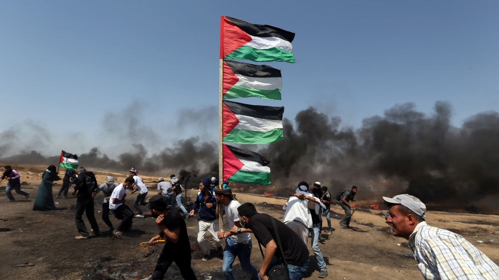 A demonstrator holds Palestinian flags as others run for cover during a protest marking al-Quds Day