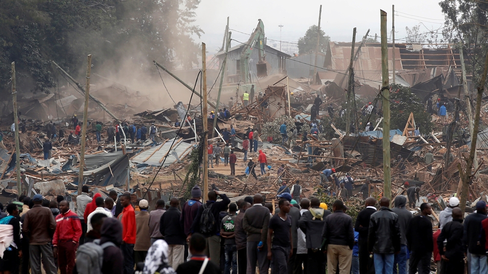 Onlookers watch as bulldozers demolish houses to make way for a new road in the Kibera slum in Nairobi, Kenya