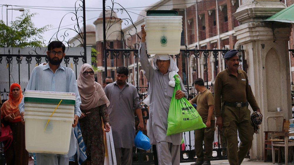 Pakistani election staff leave after collecting ballot boxes and polling material from a distribution centre in Rawalpindi [Anjum Naveed/The Associated Press]