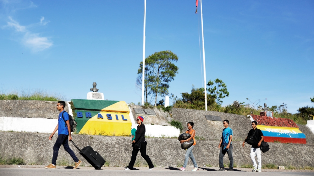 Venezuelans walk across the border from Venezuela into the Brazilian city of Pacaraima, Roraima state