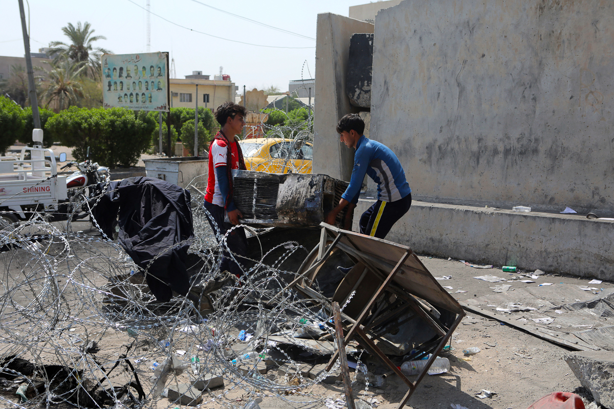 Workers throw burned furniture from burned Basra Government building in Basra, 340 miles (550 km) southeast of Baghdad, Iraq, Saturday, Sept. 8, 2018. A local military commander for an alliance of pow