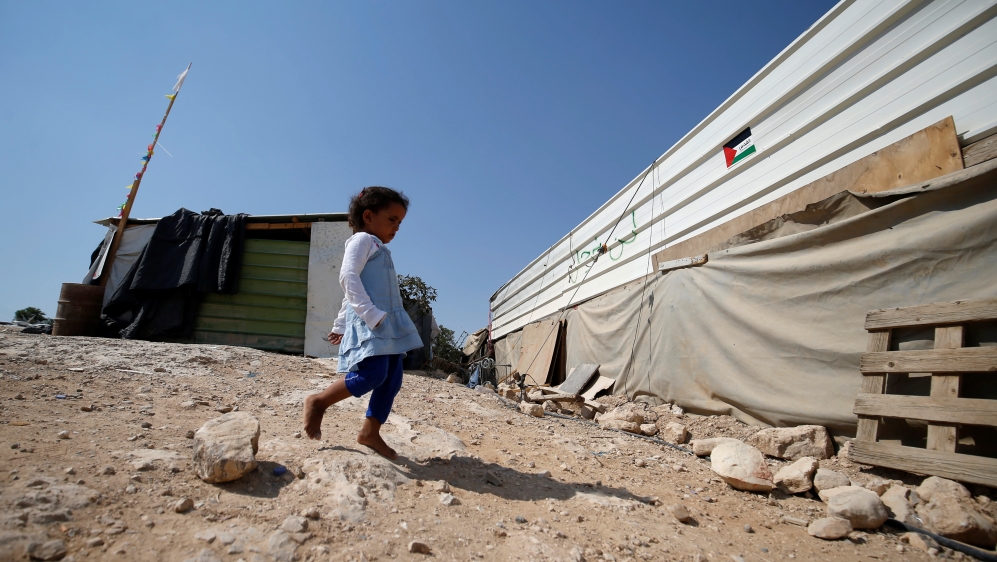 A Palestinian girl walks outside her family dwelling in Khan al-Ahmar [Mohamad Torokman/Reuters]