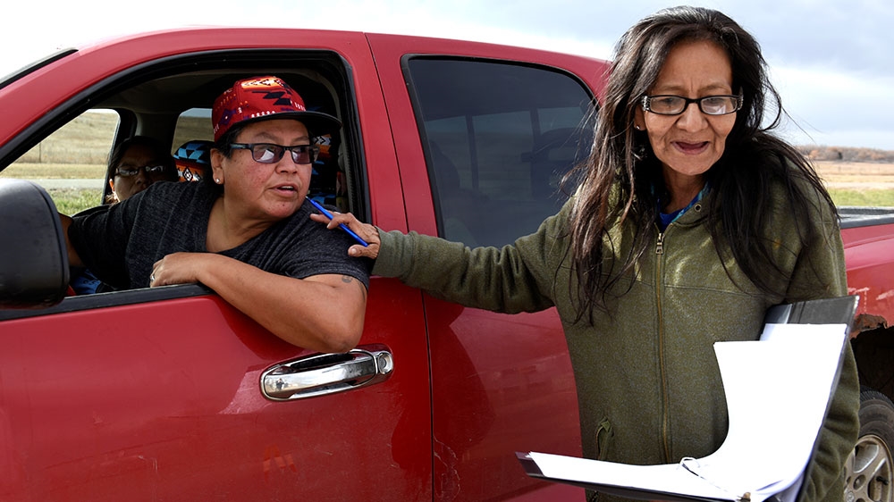 Brenda Miller speaks to a voter while canvassing voters in Porcupine, North Dakota before the 2018 midterm elections on the Standing Rock Reservation [Dan Koeck/Reuters]
