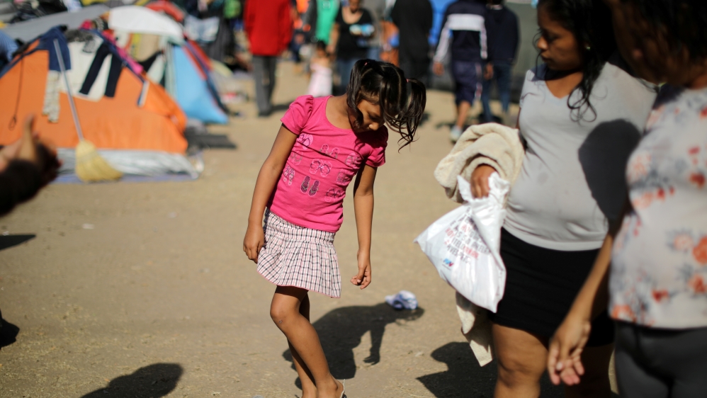 A girl tries on shoes as she waits with members of a caravan from Central America in Tijuana