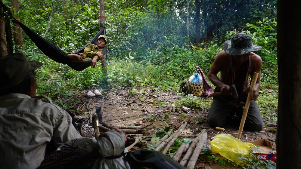 A patroller fashions a new handle for his scythe at a makeshift camp [Matt Blomberg/Al Jazeera]