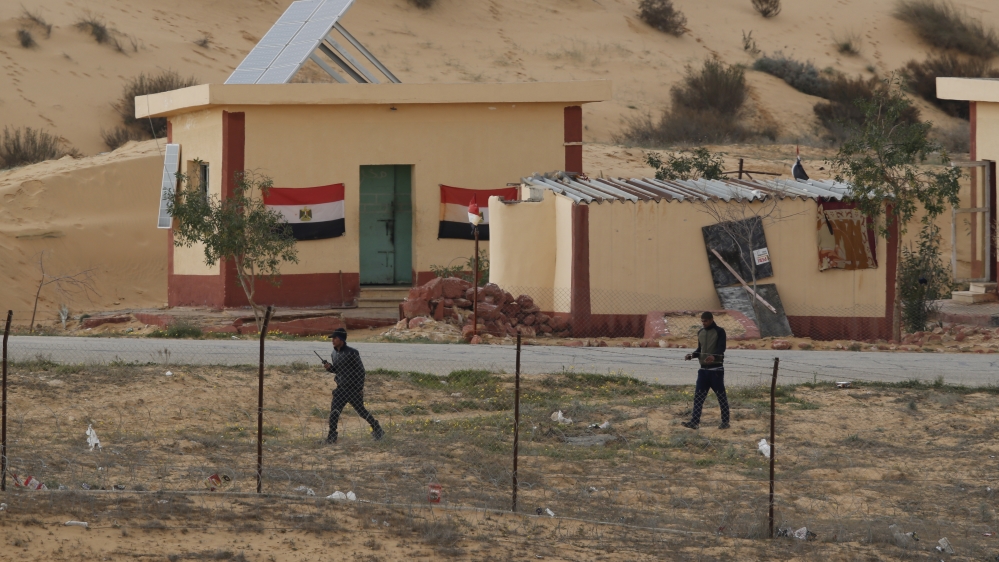 Egyptian policemen walk next to a border post, as seen from the Israeli side of the border with Egypt''s Sinai peninsula