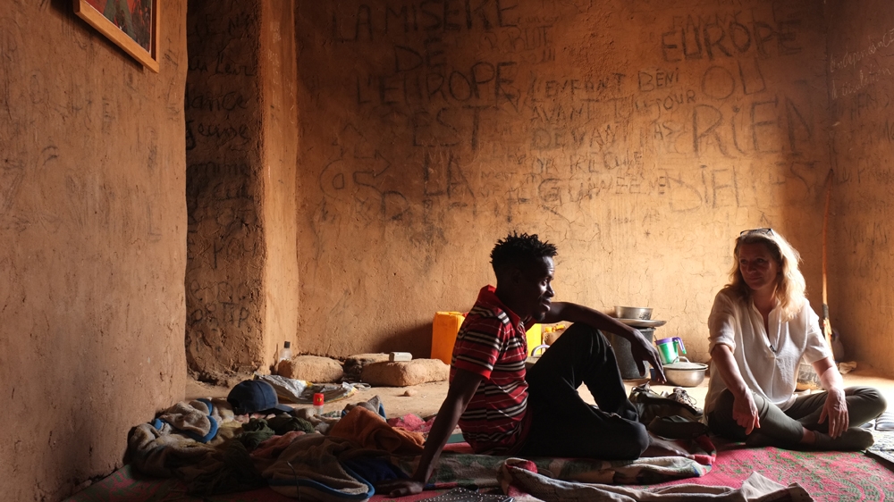 Correspondent Juliana Ruhfus with a migrant in a ghetto. Ghettos are houses where migrants hide while waiting for smugglers to organise their transport to Europe via Libya or Algeria. [Victoria Baux/Al Jazeera]