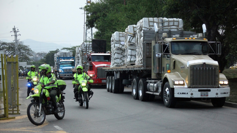 Police officers escort trucks as they arrive at a warehouse, where international humanitarian aid for Venezuela will be stored  [Carlos Ramirez/Reuters]