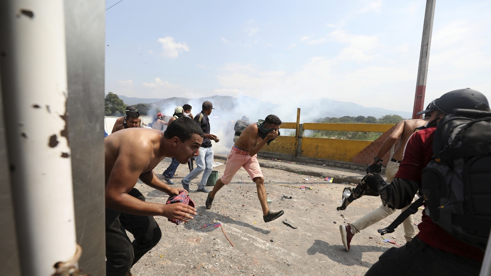 Venezuelan youth run for cover from tear gas launched by Venezuela's National Guard [Fernando Vergara/AP]