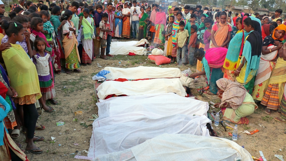 People stand next to the bodies of tea plantation workers, who died after consuming bootleg liquor, in Golaghat in the northeastern state of Assam, India, February 22, 2019