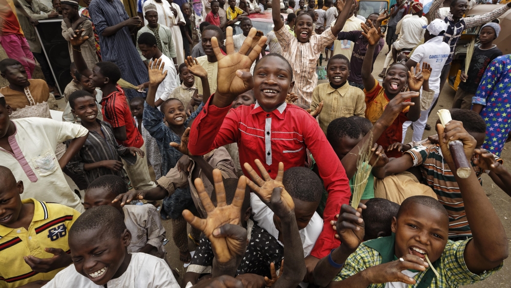 Young supporters of Buhari celebrate his electoral win, holding up four fingers to indicate 