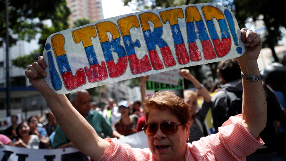 A supporter of Venezuelan opposition leader Juan Guaido holds a banner reading 'freedom' during a protest on January 30 [Carlos Garcia Rawlins/Reuters]