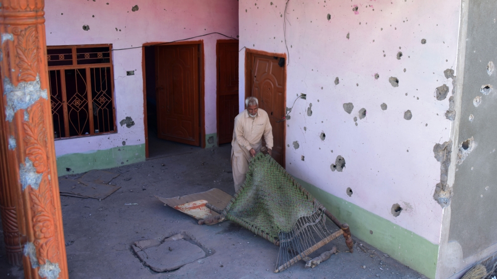 A Pakistani Kashmiri holds a damaged wooden charpai in his house beside walls riddled with bullets by cross-border firing at Dhanna village, on the LoC that divides Kashmir between Pakistan and India, on March 5, 2019 [Sajjad Qayyum/AFP] 