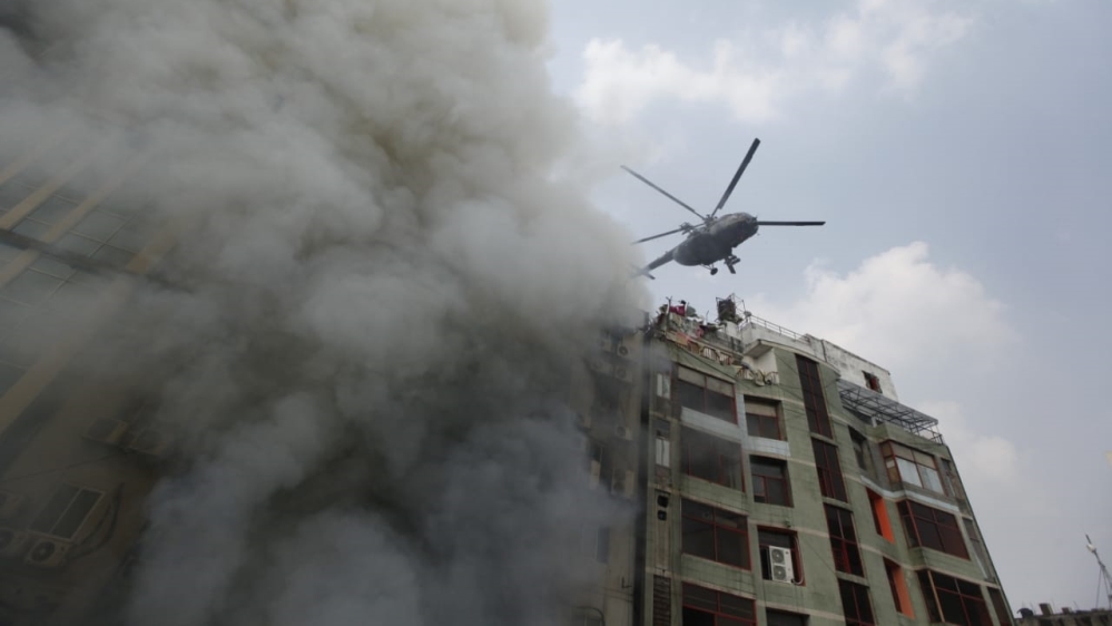 Helicopters drop water on the burning building [Mahmud Hossain Opu/Al Jazeera]