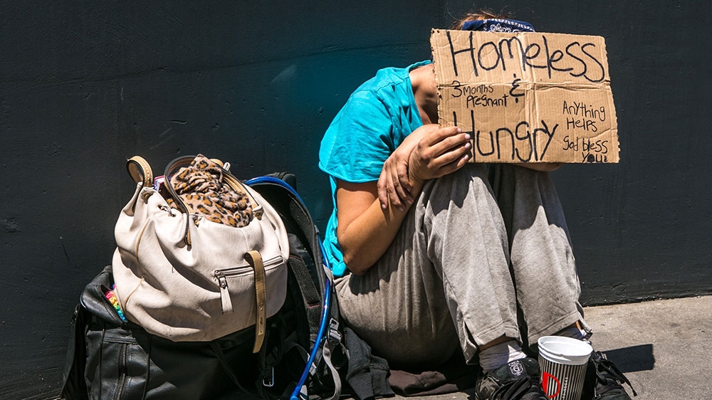 A homeless woman sits on the street in Las Vegas, Nevada [File: George Rose/Getty Images) 