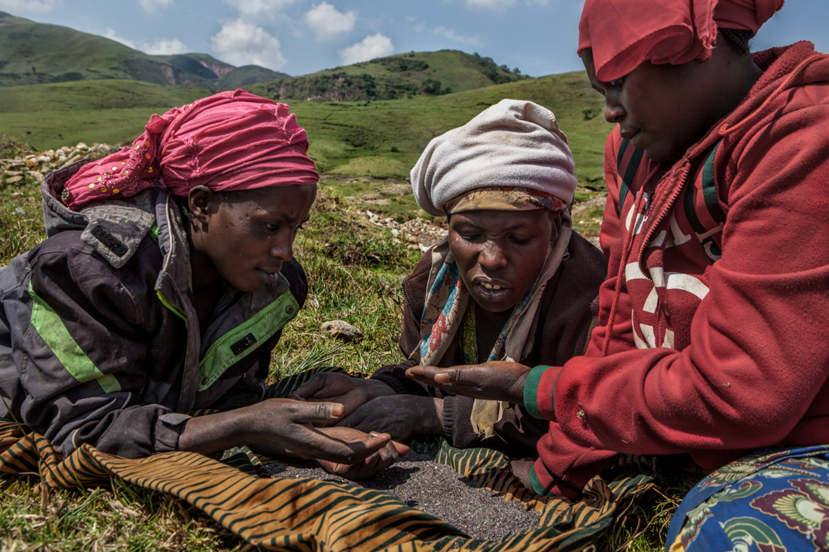 Numbi. At the end of their working day, women take some rest on the surrounding meadows and observe the quantity and quality of the stones – in this case containing cassiterite - they collected. Miner