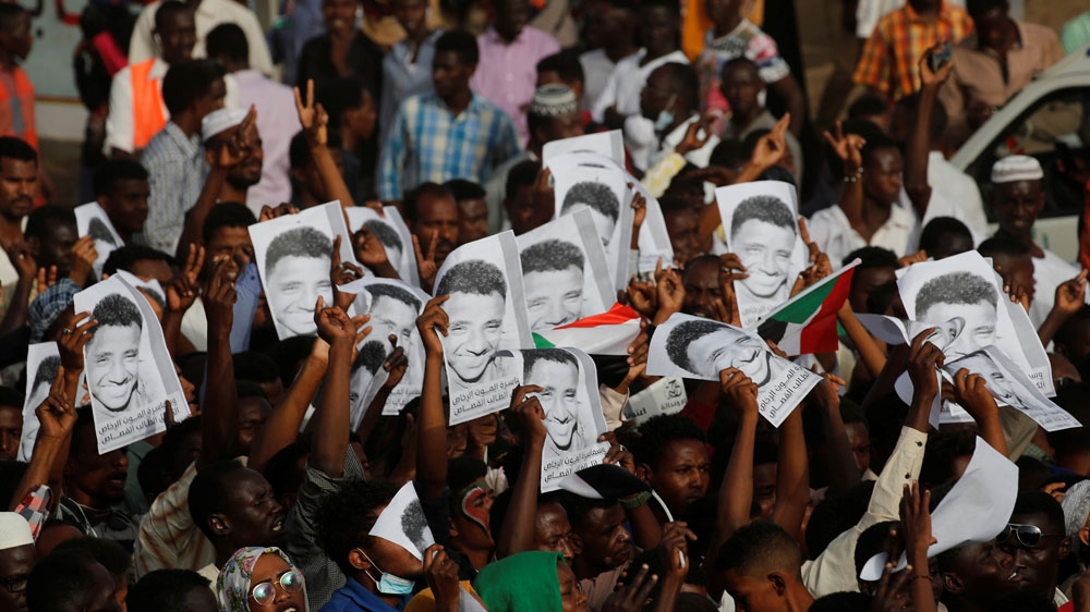 Protesters march as they carry portraits of a man who they claim was killed by an order given by former Sudanese President Omar al-Bashir, in front of the Defence Ministry in Khartoum [Umit Bektas/Reuters]