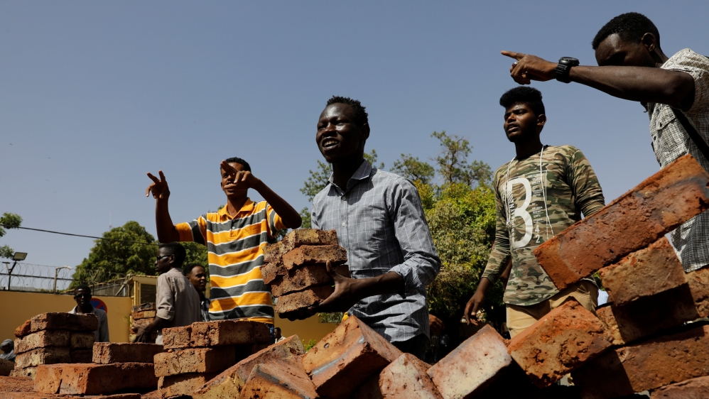 Protesters carry bricks to a barricade on a road leading to the army headquarters [Umit Bektas/Reuters]
