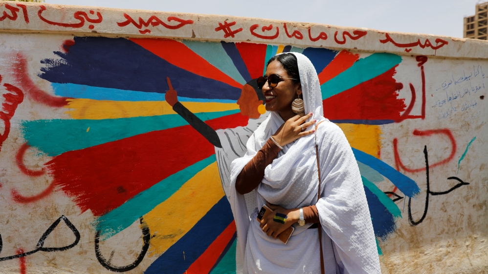 Alaa Salah, a Sudanese protester whose video gone viral and make her an icon for the mass anti-government protests, stands in front of a mural depicting her in front of the Defence Ministry, Khartoum