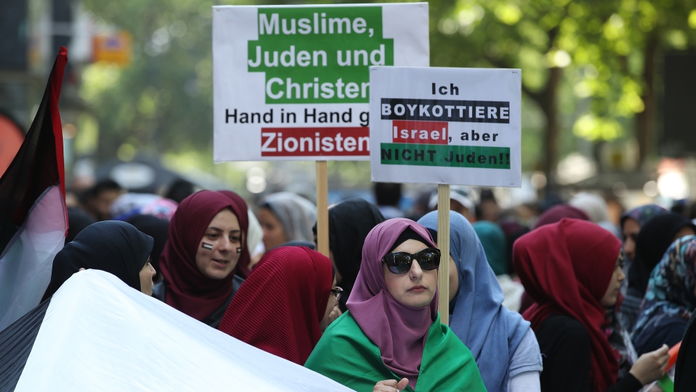 A woman holds a sign at a rally in Berlin saying ‘I boycott Israel, but not Jews!’