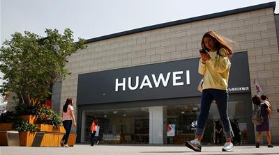 A woman looks at her phone as she walks past a Huawei shop in Beijing, China May 16, 2019. REUTERS/Thomas Peter