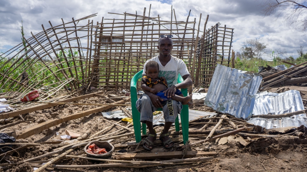 Louis Jose Batista sits with his son outside their home in Zone Seta, Macomia, demolished by Cyclone Kenneth which swept through Macomia district in northern Mozambique.