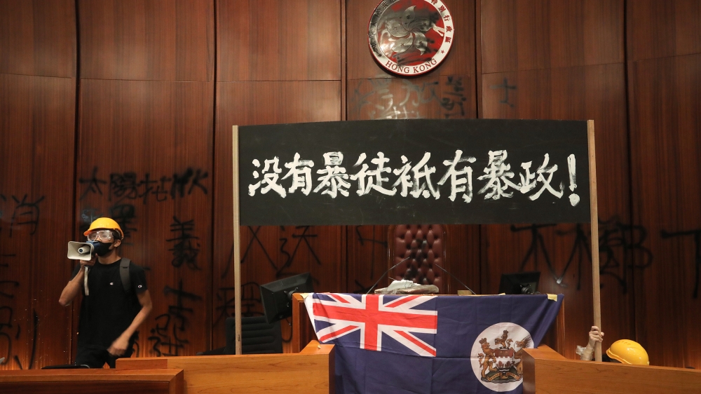 A protester uses a loudspeaker after they broke into the parliament chamber of the government headquarters and tied a British colonial flag to the podium in Hong Kong on July 1, 2019, on the 22nd anni