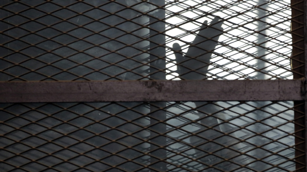 In this Aug. 22, 2015 file photo, a Muslim Brotherhood member waves his hand from a defendants cage in a courtroom in Torah prison, southern Cairo, Egypt. Amnesty International said Wednesday, July 31