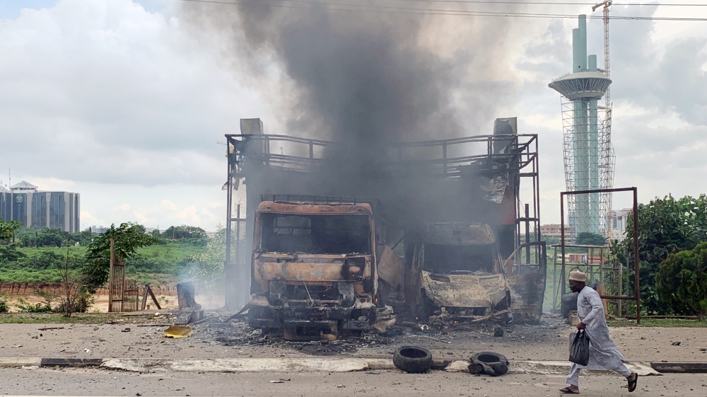 A man runs past burning vehicles after clashes between police and Shi'ite protesters in Abuja
