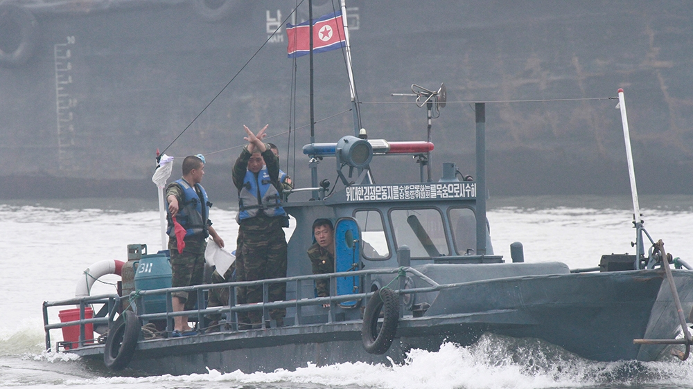 North Korean policemen gesture as they ask a North Korean fish boat to stop for inspection on the Yalu River near the North Korean town of Sinuiju, opposite the Chinese border city of Dandong, July 7,