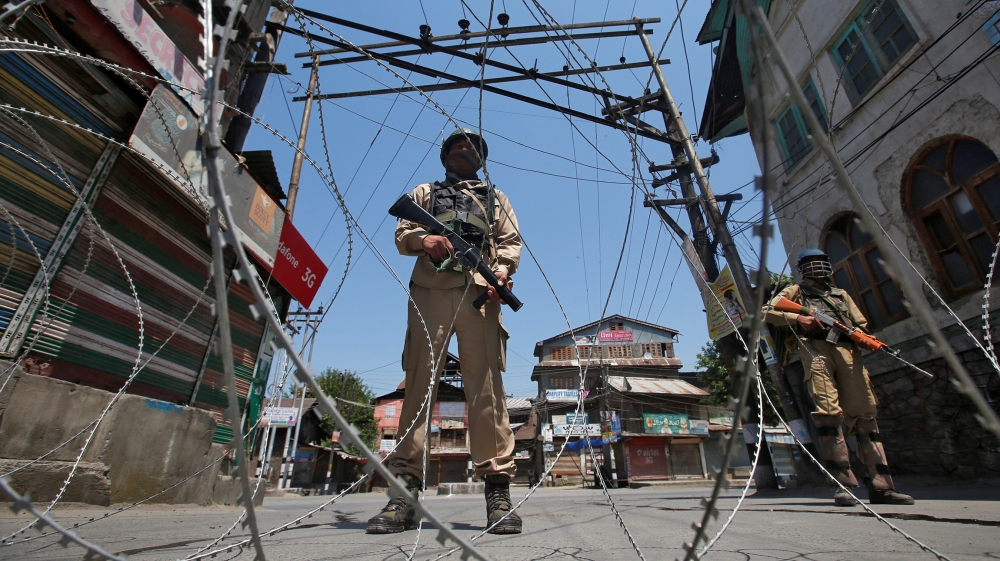 Indian policemen stand guard behind concertina wire during a strike called by separatists to mark the death anniversaries of chief cleric of Kashmir, Moulana Mohammad Farooq and Abdul Gani Lone, a Kas