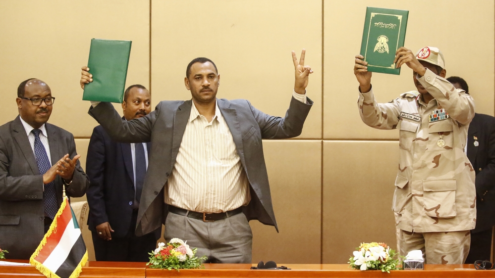 L to R) Ethiopian mediator Mahmoud Drir, protest leader Ahmad Rabie, and General Mohamed Hamdan Daglo, Sudan''s deputy head of the Transitional Military Council, celebrate after signing the constitutio